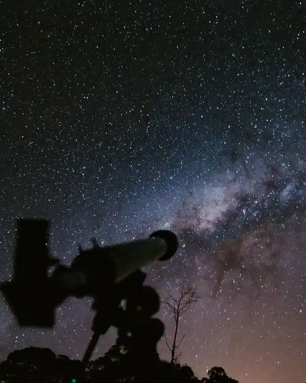 Gece gökyüzüne çevrilmiş teleskobun kırmızı ışıkta beliren silueti